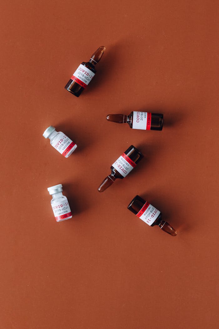 Top view of COVID-19 vaccine vials on a brown surface, arranged in a flat lay.